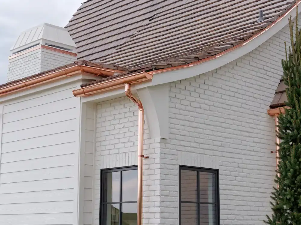 Copper gutters on a white brick house, illustrative of the upgrades possible through gutter repair and replacement.